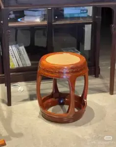 Ming-style red wooden stool with woven seat, showcasing light and shadow