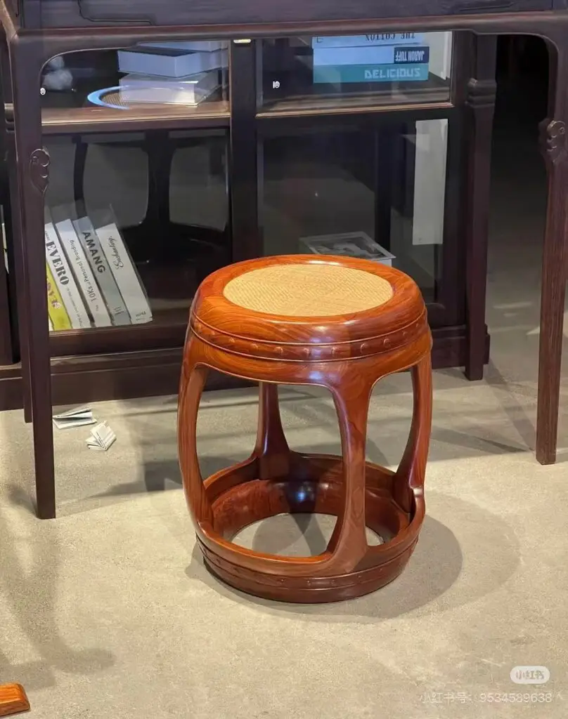 Ming-style red wooden stool with woven seat, showcasing light and shadow